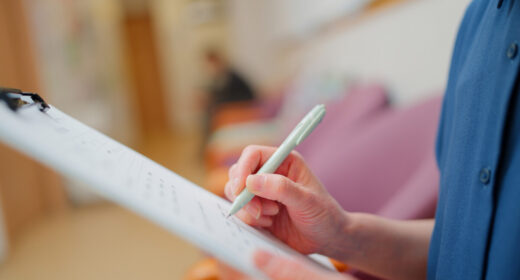 A patient fills out a form on a clipboard.