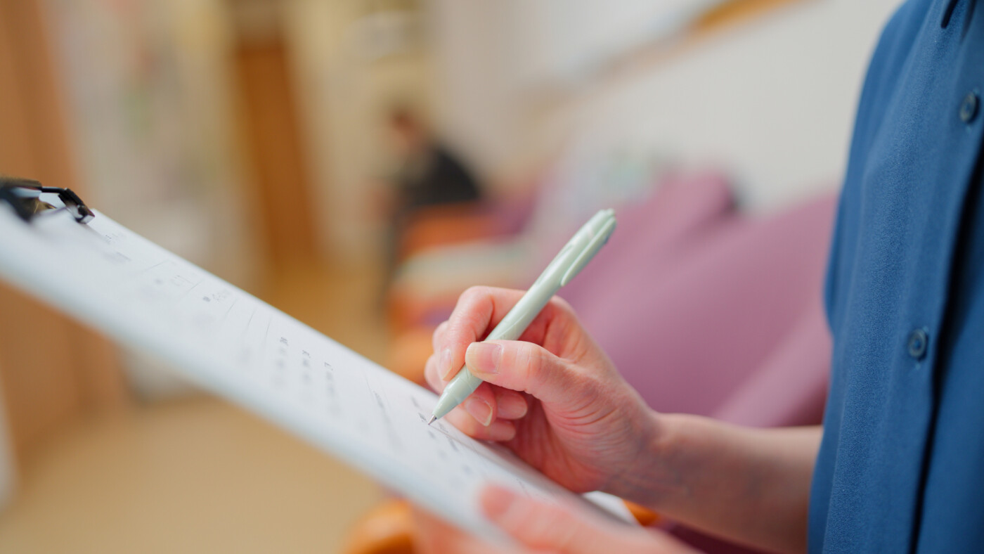 A patient fills out a form on a clipboard.