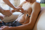 A person adjusts a stimulating device on another person's chest.