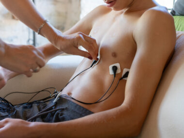 A person adjusts a stimulating device on another person's chest.