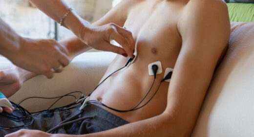 A person adjusts a stimulating device on another person's chest.
