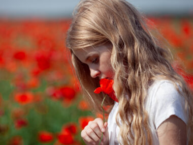 A photo shows a girl sniffing a flower.