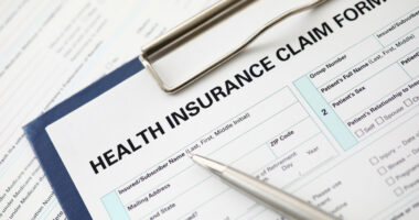 A pen sits on an insurance form on a clipboard.