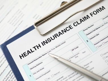 A pen sits on an insurance form on a clipboard.