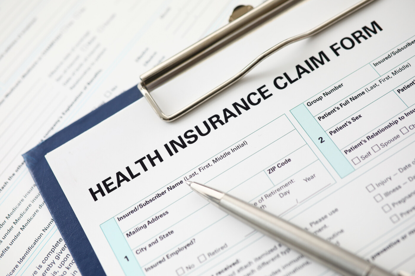A pen sits on an insurance form on a clipboard.